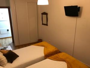 ポンタ・デルガダにあるCosta Apartmentsのベッドルーム1室(ベッド2台、壁掛けテレビ付)
