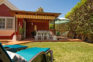 a patio with a table and chairs and an umbrella at Bungalow Tunos Maspalomas in San Bartolomé
