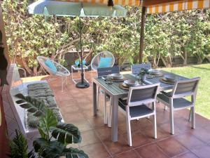a patio with a table and chairs and an umbrella at Bungalow Tunos Maspalomas in San Bartolomé +36 photos