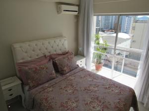 sypialnia z łóżkiem i dużym oknem w obiekcie Apartamento Coral - 1 quadra do Mar w mieście Balneário Camboriú