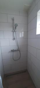 La salle de bains carrelée de blanc est pourvue d'une douche et d'une fenêtre. dans l'établissement Logies Plevierstraat, à De Koog