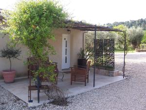 pergola z dwoma krzesłami i ławką przed domem w obiekcie OUSTAOU DU GAYET gîte de charme avec piscine privée w mieście Lourmarin