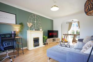 ein Wohnzimmer mit einem blauen Sofa und einer Uhr an der Wand in der Unterkunft Grange House with Free Parking, Garden, Superfast Wifi and Smart TVs with Netflix by Yoko Property in Northampton