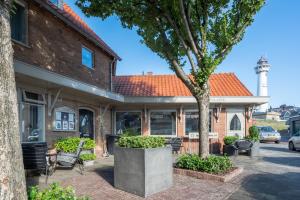 una vieja casa de ladrillo con un árbol delante en La Chatelaine en Egmond aan Zee