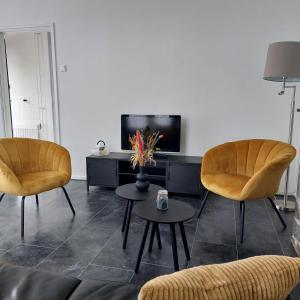 a living room with two chairs and a tv at Hof Christina Vakantiewoningen in Vrouwenpolder