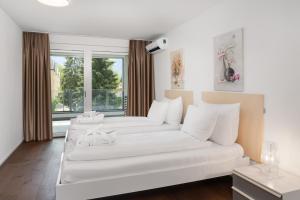 uma sala de estar com dois sofás brancos e uma janela em Swiss Hotel Apartments - Interlaken em Interlaken
