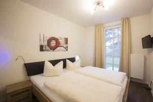 Schlafzimmer mit einem Bett mit weißer Bettwäsche und einem Fenster in der Unterkunft Residenz am Balmer See - BS 03 mit Wellnessbereich in Balm