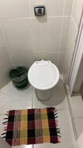 a bathroom with a toilet and a rug on the floor at Suite Ilha Grande in Angra dos Reis