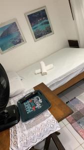 a bed with a table with a cell phone on it at Suite Ilha Grande in Angra dos Reis