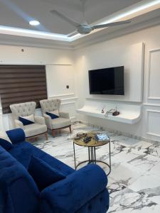 a living room with a blue couch and a tv at HMS SEA VIEW VILLA in Accra