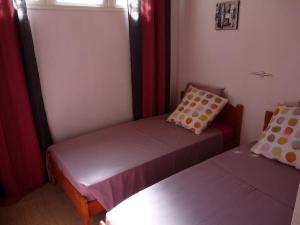 two beds in a small room with red curtains at petite maison traditionnelle in Saint-Leu