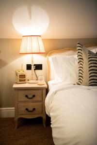 um quarto com uma cama e um candeeiro numa mesa de cabeceira em The Cotley Inn em Wambrook