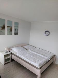 ein weißes Schlafzimmer mit einem Bett und einem Beistelltisch in der Unterkunft Utkiekerblick 9217 Burgtiefe in Fehmarn