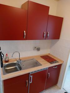 eine Küche mit roten Schränken und einem Waschbecken in der Unterkunft Utkiekerblick 9217 Burgtiefe in Fehmarn