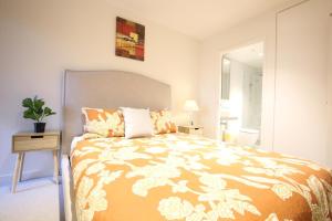 a bedroom with a bed with a orange and white comforter at Dudley Cosy 2 beds 2 Baths with free parking in Melbourne