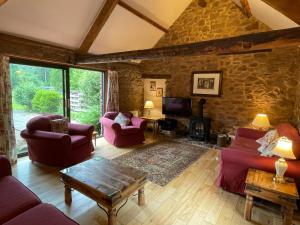 a living room with red furniture and a stone wall at Duddings Country Cottages in Minehead