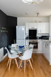 a kitchen with a glass table and white chairs at Modern & Spacious flat in the Centre of Bristol! in Bristol