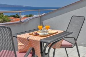einen Tisch mit zwei Gläsern Orangensaft auf dem Balkon in der Unterkunft Villa Juric in Baška Voda