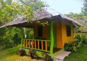 uma pequena casa amarela e verde com telhado de palha em La Villa Alta em Siquijor