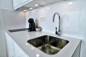 una cocina con fregadero de acero inoxidable en una encimera blanca en Apartamentos La Perla Azul, en Málaga