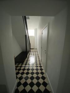 korytarzem z czarno-białą podłogą wyłożoną szachownicą w obiekcie “De Koelemert” w mieście Aalst