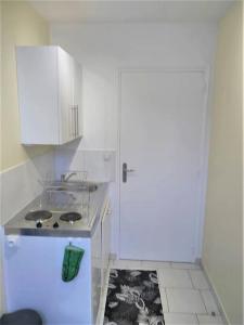 uma pequena cozinha com um fogão e um armário branco em SOUS LES TOITS em Troyes