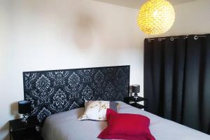 um quarto com uma cama com uma almofada vermelha em SOUS LES TOITS em Troyes
