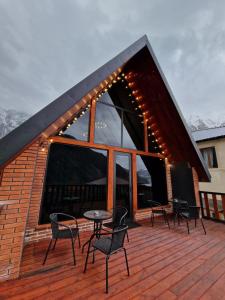 a deck with chairs and a table on a building at Kazbegi Hut Cottage in Kazbegi