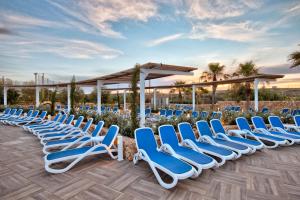 a row of blue lounge chairs on a patio at db Seabank Resort + Spa All Inclusive in Mellieħa