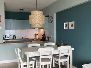 een keuken met een witte tafel en witte stoelen bij Zeezicht Blankenberge in Blankenberge