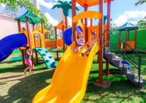 two children sitting on a slide at a playground at Mavsa Resort in Cesário Lange