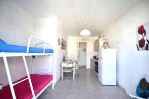 ein kleines Zimmer mit 2 Etagenbetten und einer Küche in der Unterkunft Alba two-room air-conditioned holiday home for 4 guests in Torre dell'Orso