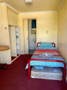 um pequeno quarto com uma cama com uma moldura vermelha em Royal Mail Hotel - Meekatharra em Meekatharra