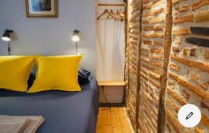 ein Schlafzimmer mit einer Ziegelwand und einem Bett mit gelben Kissen in der Unterkunft Maison centre historique Le Préau saint Jacques in Castres