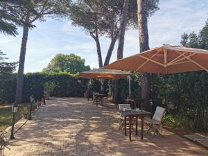 un patio con tavoli, sedie e ombrellone di B&B Parco degli Ulivi a Misano Adriatico