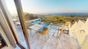 uma varanda com uma mesa e cadeiras e o oceano em Dubhlina - Luxury Bed & Breakfast - Gozo em Żebbuġ