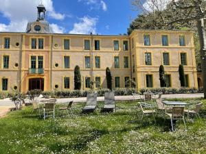 un edificio con mesas y sillas delante de él en La Mascotte des thermes de Montbrun les bains, en Montbrun-les-Bains