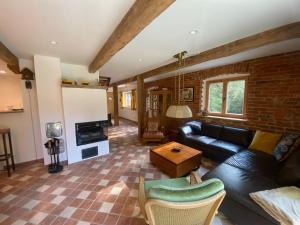 a living room with a black leather couch and a fireplace at Das Hexenhaus: Haus im Wald in Rinchnach