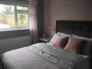 una camera da letto con un letto con cuscini rosa e una finestra di The Marches, Ludlow a Ludlow