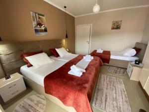 Cette chambre d'hôtel comprend 2 lits avec des draps rouges et blancs. dans l'établissement Guest's Apartament, à Pogradec