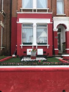 a red house with a window and flowers in front of it at Dream Nest in Southend-on-Sea