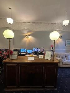 a desk with three monitors and two lamps on it at Thanet Hotel Annex in London