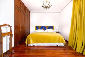 1 dormitorio con cama amarilla y cortinas amarillas en La Ideal Mansion by VillaGranCanaria, en Tafira