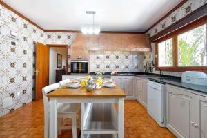 cocina con armarios blancos y mesa de madera en La Ideal Mansion by VillaGranCanaria, en Tafira