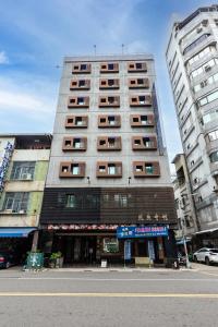 a tall building on a city street with buildings at I HI Sanduo Travel Hotel in Kaohsiung