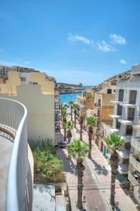 einen Balkon mit Blick auf eine Straße mit Palmen in der Unterkunft Seaside apartment in the heart of Xlendi Gozo in Xlendi