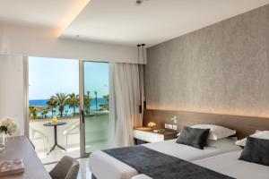 a hotel room with two beds and a balcony at Pavlo Napa Beach Hotel in Ayia Napa