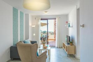 sala de estar con sofá, silla y TV en Andaluz Apartments Mar de Nerja, en Nerja