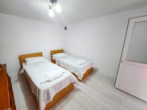 two beds in a room with white walls and wooden floors at Casă de vacanță Danube in Moldova Nouă +11 photos