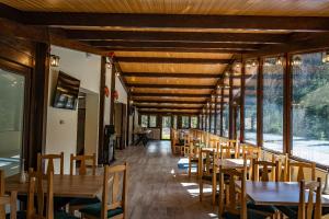 un restaurante con mesas y sillas de madera y ventanas en PENSIUNEA SKY HUB en Arieşeni
